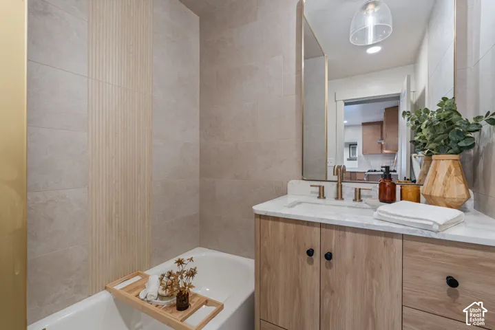 Built-in bathtub with tiled surround featuring a vertical accent strip