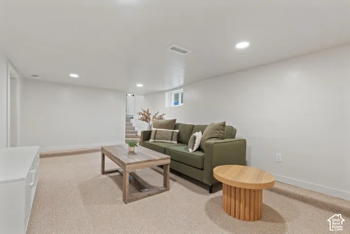 Recessed lighting, light-colored carpeting, white painted walls, and a window providing natural light