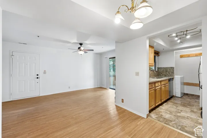 Wood-finish flooring throughout, ceiling fan with integrated lighting, recessed lighting, and kitchen featuring wood cabinetry and stone countertops