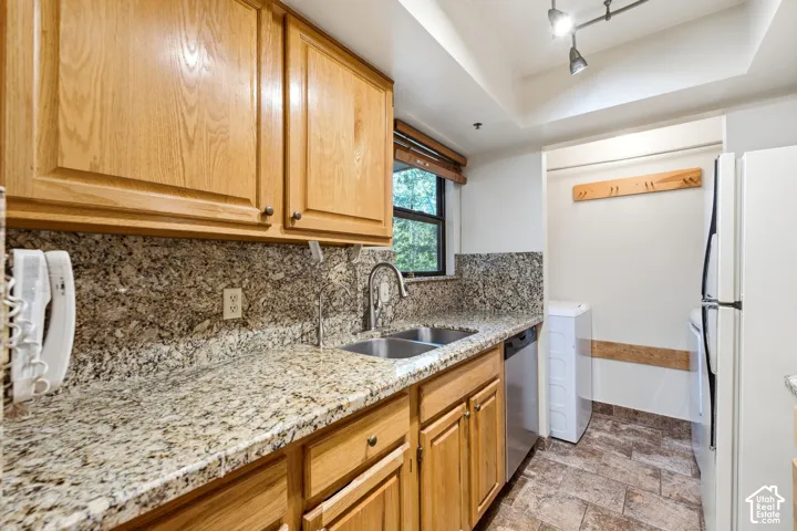 Kitchen featuring wood cabinetry, granite countertops, stainless steel double basin sink, and tile flooring