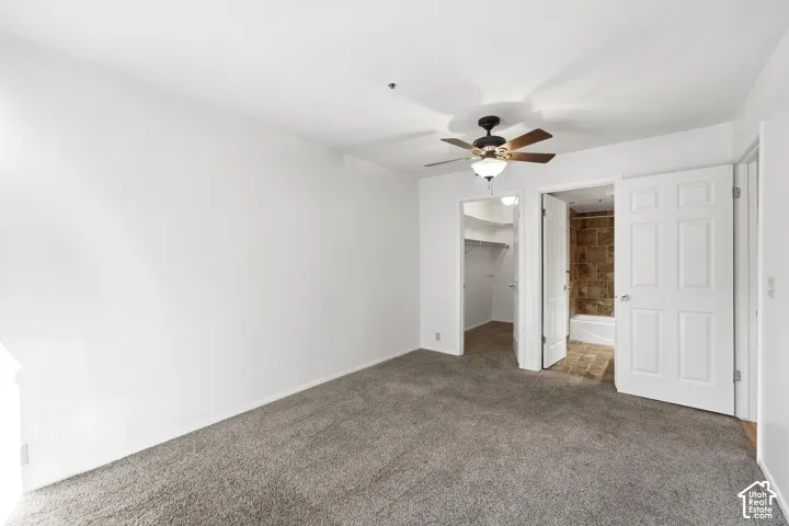 Carpeted room with a ceiling fan, white paneled doors, and access to a closet