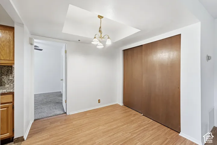 Wood-finish flooring with a recessed ceiling and overhead chandelier