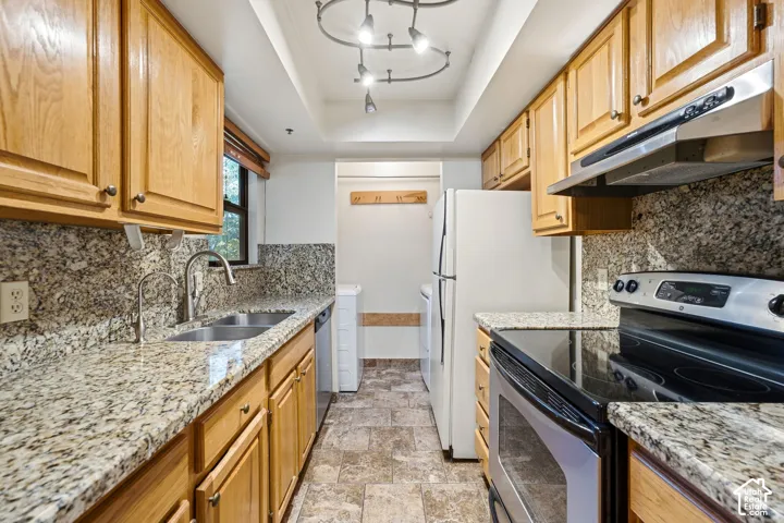 Galley kitchen featuring light wood-finish cabinetry, granite countertops, and stainless steel appliances