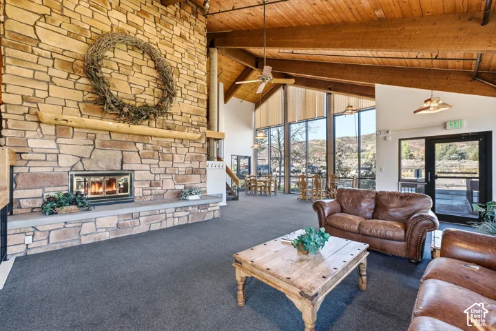 Stone-faced fireplace with hearth, wood beam mantle, and wood-finish ceiling