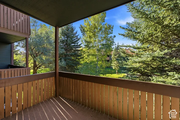 Covered outdoor balcony with wood plank flooring and wood railing