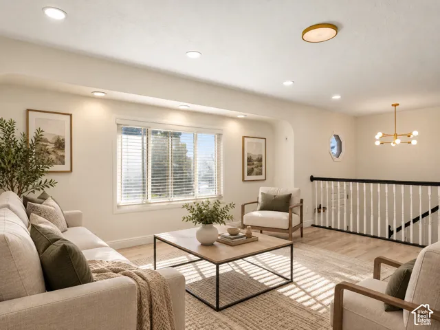 Recessed lighting, large window with blinds, wood-finish flooring, white spindle railing with dark handrail, and a modern gold chandelier. Virtually Staged
