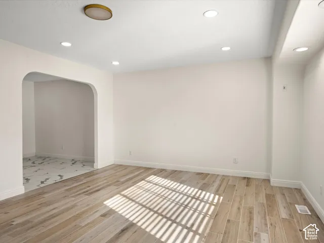 Wood-finish flooring, recessed lighting, arched doorway, and a flush mount ceiling fixture