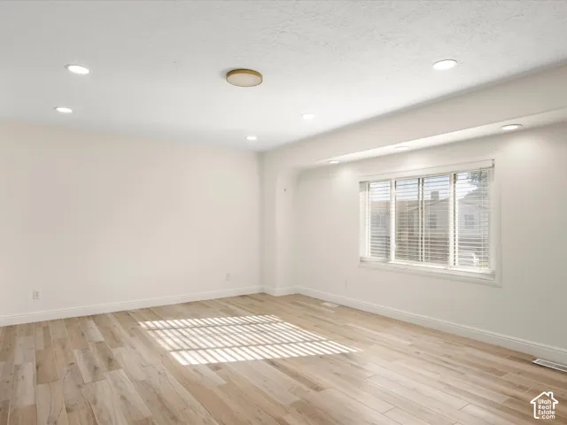 Recessed ceiling lighting, wood-finish flooring, and a large window with blinds