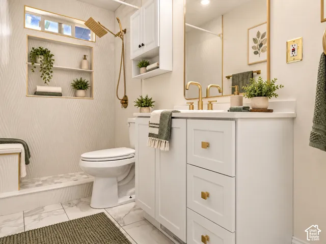 White shaker-style vanity with gold-tone hardware, white countertop, and under-mount sink. Virtually Staged