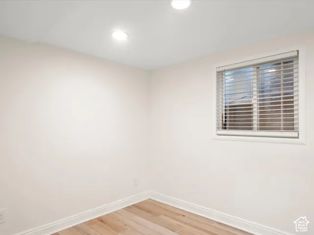 Recessed ceiling lighting, a window with horizontal blinds, wood-finish flooring, and white trim