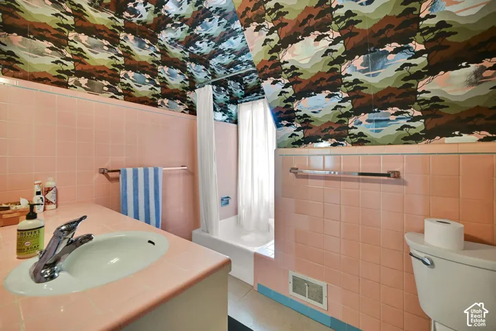 Built-in vanity with integrated sink, chrome faucet, and pink tiled countertop