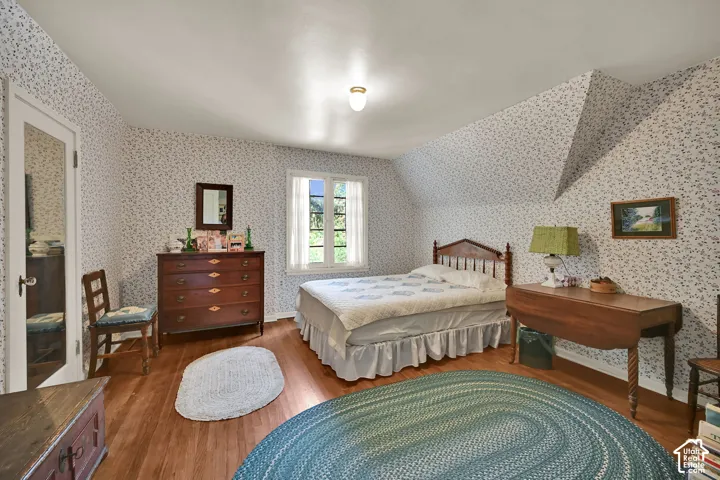 Hardwood flooring, sloped ceiling, window with exterior light, overhead light fixture, paneled door