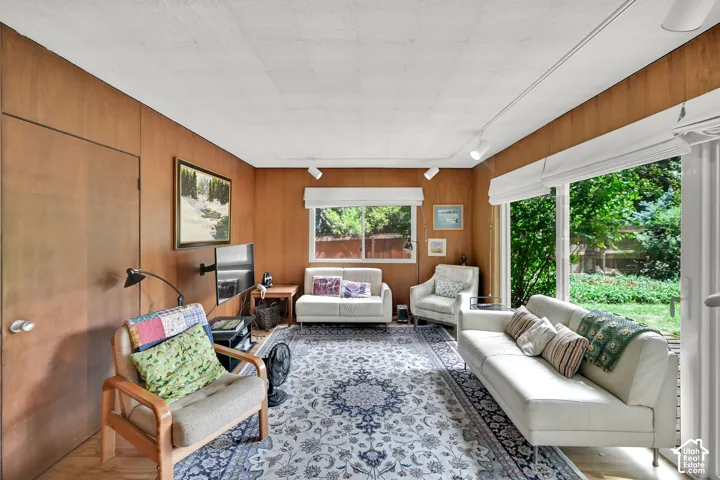 Wood-paneled walls with track lighting, large windows, and a full-light glass door