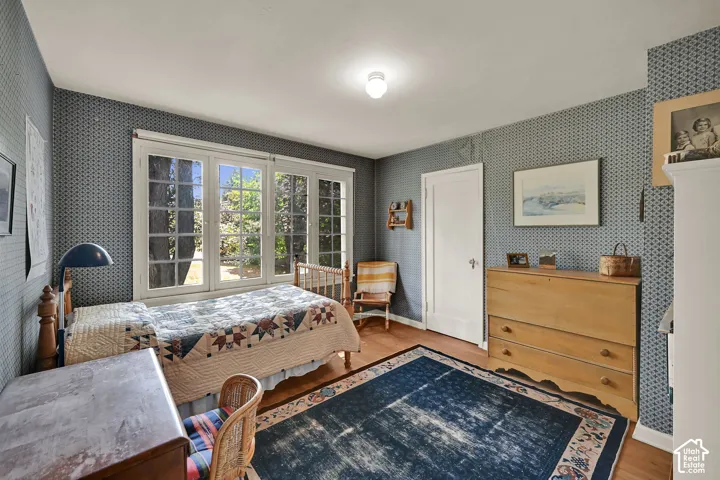 Hardwood flooring, patterned wallpaper, white trim, and a white interior door