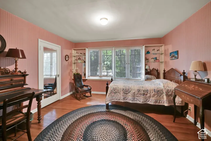 Hardwood flooring, multiple windows, built-in shelving, and a mirrored door