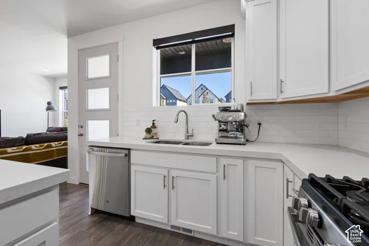 White shaker cabinetry, light-toned countertops, white subway tile backsplash, stainless steel appliances, and wood-finish flooring