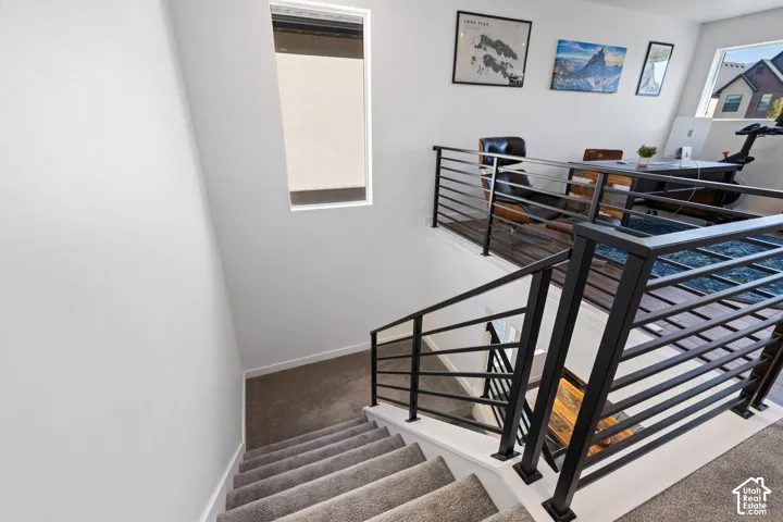 Staircase featuring carpeted treads, contemporary black metal railings, and a landing with wood-finish flooring