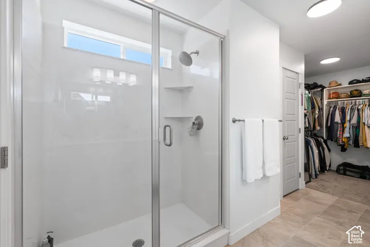 Glass-enclosed shower with a rainfall showerhead, integrated shelving, and a transom window