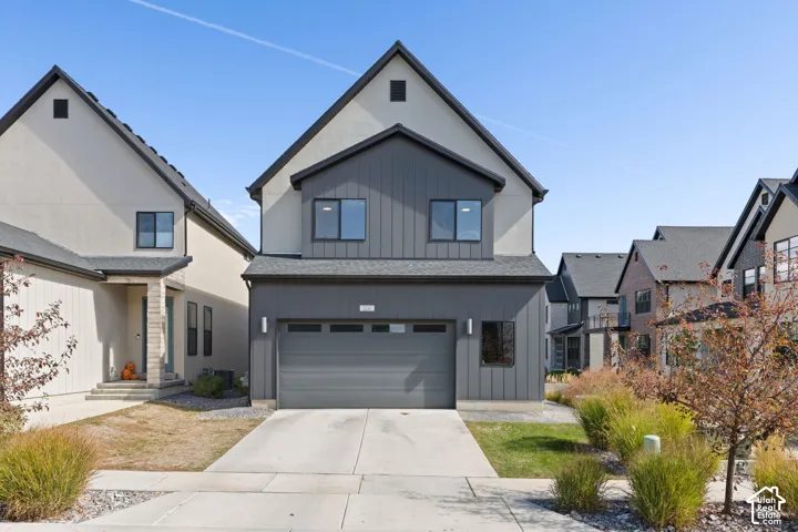 Two-story exterior with a mix of light-toned stucco and vertical dark siding