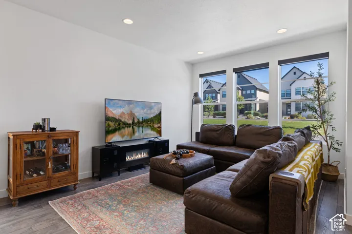 Living area featuring recessed lighting, a modern electric fireplace, wood-finish flooring, and multiple large windows