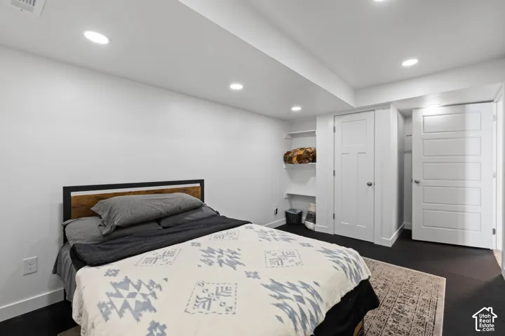 Recessed ceiling lighting, white walls, dark wood-finish flooring, built-in shelving, and white interior doors