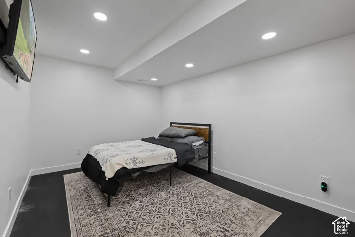 Recessed lighting illuminates the room, featuring painted walls and dark flooring