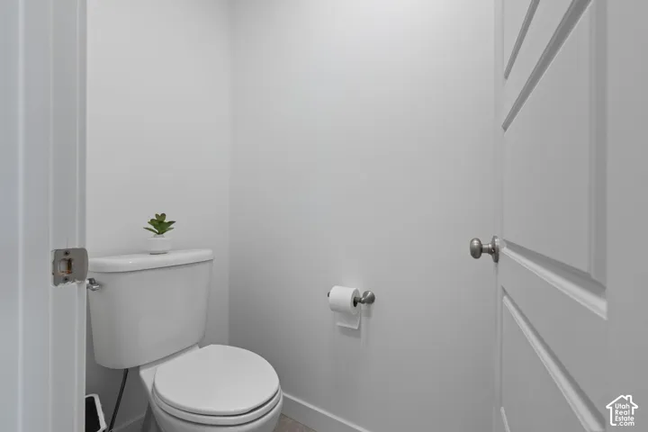 White toilet with a round bowl, brushed nickel toilet paper holder, and a white interior door with horizontal paneling