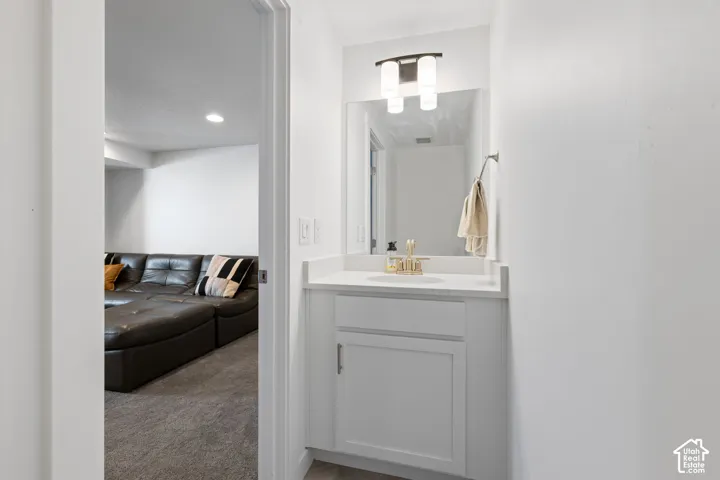 White vanity with a single basin, gold-finish faucet, and coordinating cabinet hardware