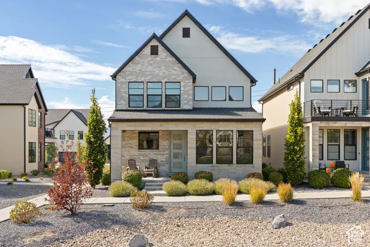 Contemporary exterior featuring a stone and siding facade, a covered entry, and a symmetrical roofline