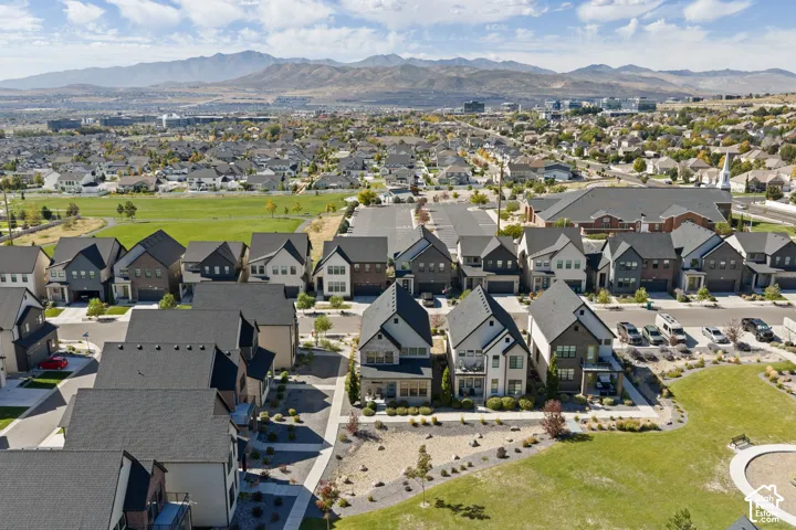 Residential community featuring single-family homes with pitched roofs, surrounded by green spaces and distant mountain ranges