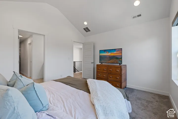 Vaulted ceiling with recessed lighting, gray carpet flooring, white walls, and a window with white trim