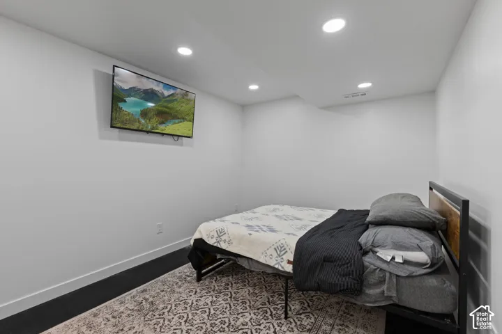 Recessed ceiling lighting, white painted walls, and dark wood-finish flooring