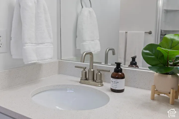 Integrated vanity sink with a light-toned countertop, brushed nickel faucet, and wall-mounted mirror
