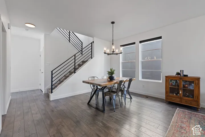 Spacious room with wood-finish flooring, white walls, and a modern chandelier
