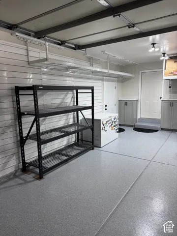 Epoxy-coated flooring, built-in cabinetry, overhead storage racks, and slatwall organization system