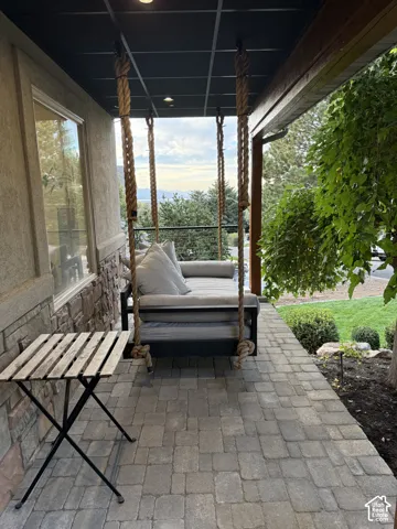 Covered porch featuring a paver walkway, stone accent wall, and recessed lighting