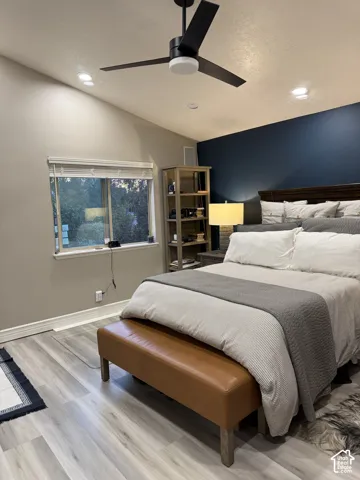 Vaulted ceiling with a contemporary ceiling fan and recessed lighting, light wood-finish flooring, and a window with blinds