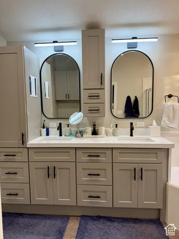 Dual sink vanity with light gray shaker cabinetry, white countertop, and matte black hardware