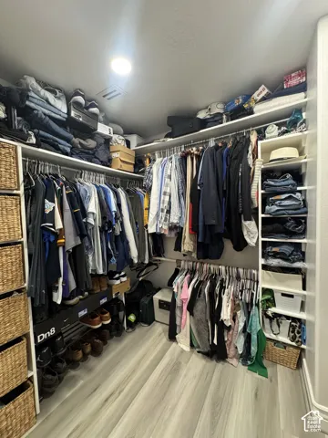 Custom closet system with multiple hanging rods, built-in shelving, and wood-finish flooring