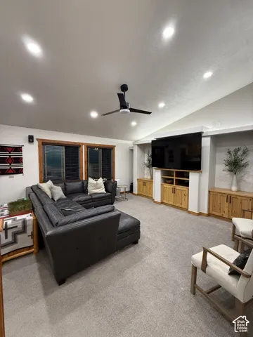 Vaulted ceilings with recessed lighting, built-in media console, and built-in wood-finish cabinetry