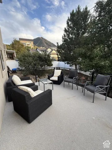 Spacious outdoor deck featuring a light-colored, textured surface and a black metal railing