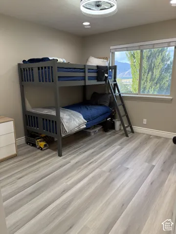 Recessed lighting, contemporary ceiling fan, light-toned wall paint, wood-finish flooring, and a large window with natural light