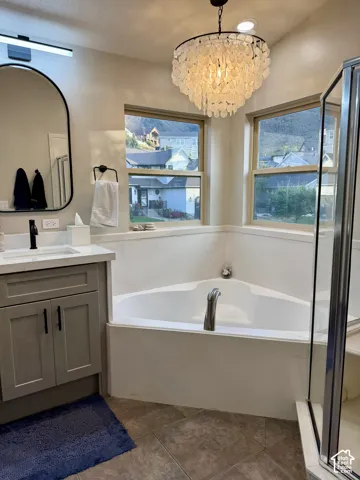 Corner soaking tub with dual windows and a decorative chandelier