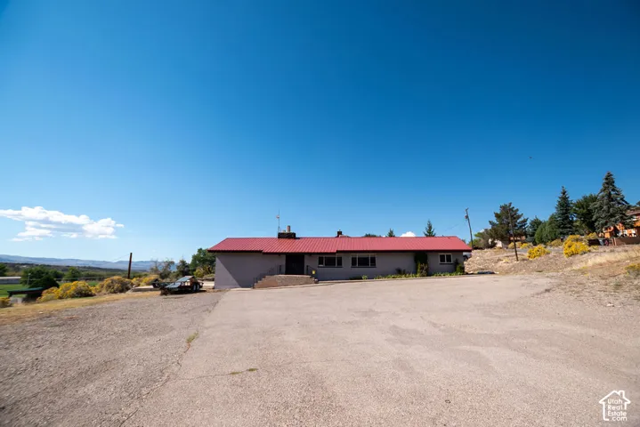 Single-story structure with a red roof, a driveway, and an expansive gravel area