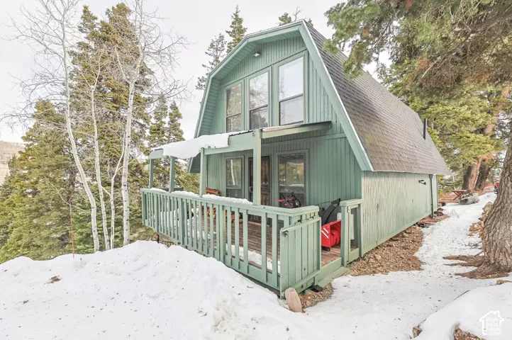 Gable roofline with an extended overhang, featuring a raised deck with a wooden railing