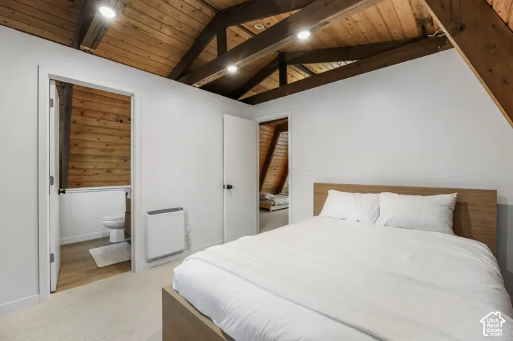 Vaulted wood-paneled ceiling with exposed beams, white painted walls, and carpet flooring