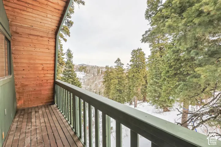 Wood-paneled balcony with wood-plank flooring and a painted wood railing, offering expansive tree-lined scenery