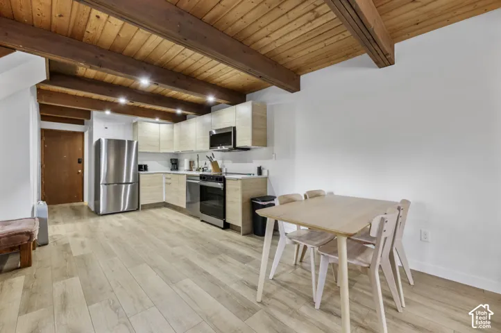 Exposed wood beam ceiling, wood-finish flooring, modern kitchen cabinetry, stainless steel appliances, and recessed lighting