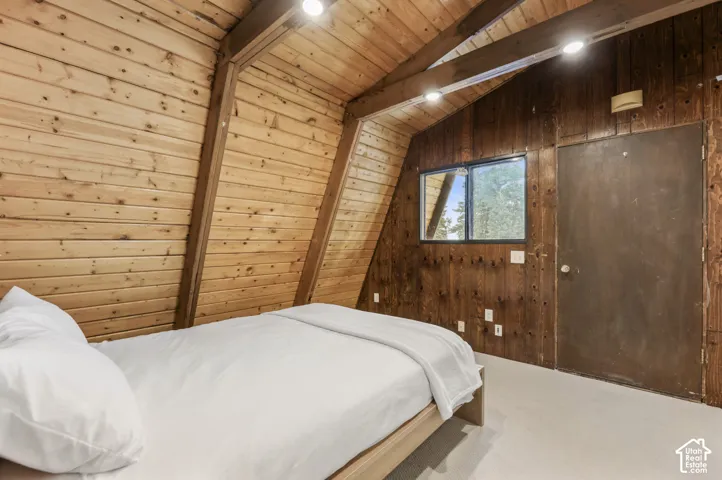 Vaulted wood-paneled ceiling with exposed beams, wood-plank walls, recessed lighting, and a window