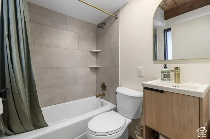 Subway tile shower surround with integrated corner shelving, white bathtub, wood-finish vanity with single-hole faucet, and arched mirror